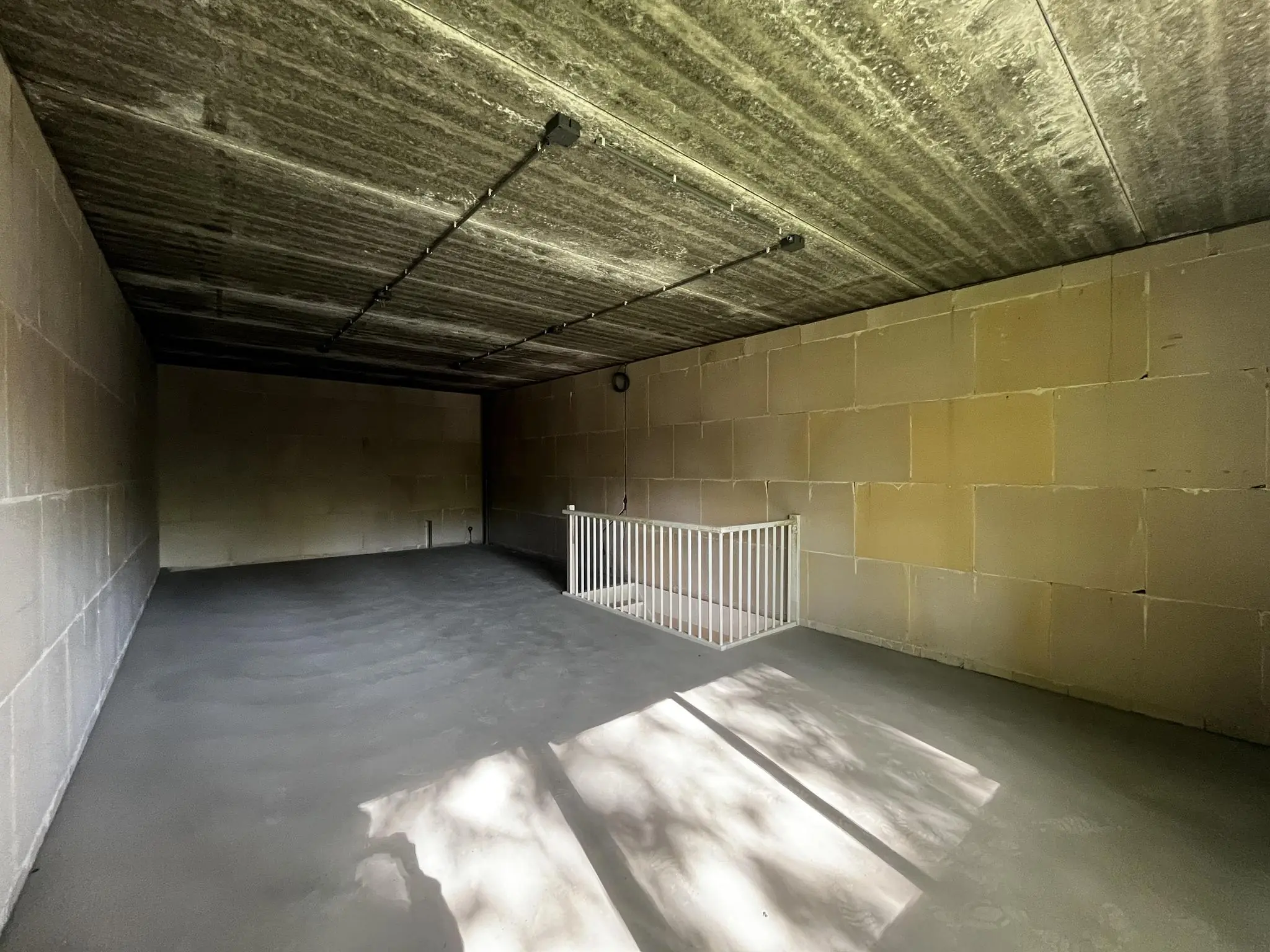 Betonnen ruimte aan de Broekdijk West met onafgewerkte wanden en plafond, en een witte trapafscherming.